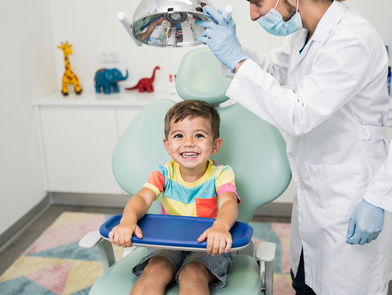 Friendly pediatric dentist smiling with a young patient in a comfortable chair